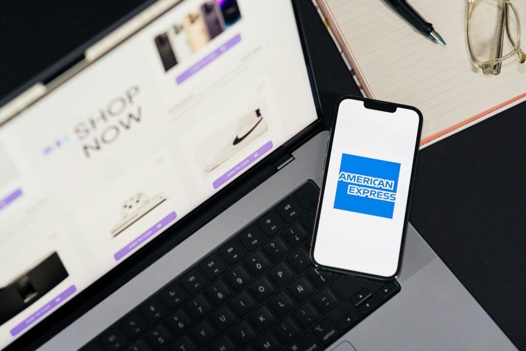 Smartphone displaying American Express logo on a laptop for online shopping convenience. Payment Gateway Integration