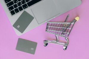A minimalist flat lay of a credit card, laptop, and miniature shopping cart. How to Start an E-commerce Business in USA