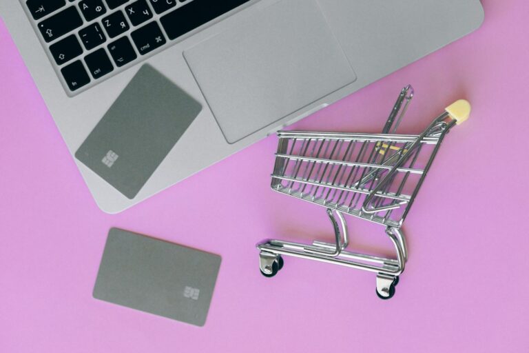 A minimalist flat lay of a credit card, laptop, and miniature shopping cart. How to Start an E-commerce Business in USA